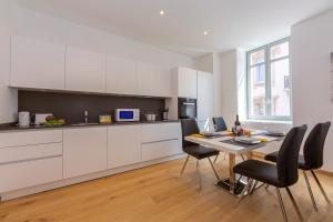 a kitchen with white cabinets and a table with chairs at Heart of Lugano - Happy Rentals in Lugano