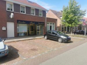 una macchina nera parcheggiata di fronte a un edificio di mattoni di Dorpszicht Yerseke centrum a Yerseke