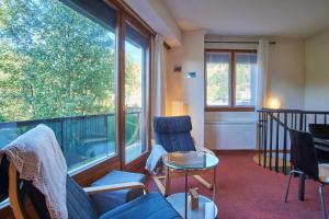 a living room with chairs and a large window at Le Vernon in Chamrousse