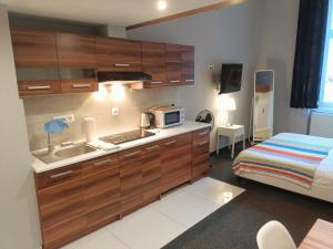a kitchen with wooden cabinets and a sink and a bed at TLC Apartments Cracow in Kraków