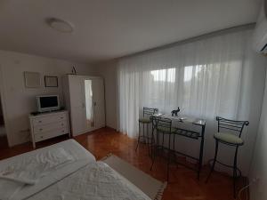 a room with a table and chairs and a bedroom at Centar apartman - gradski trg in Gornji Milanovac
