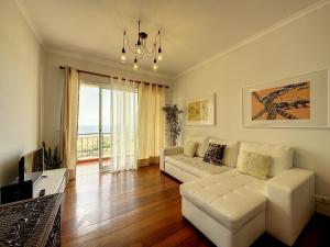 een woonkamer met een witte bank en een televisie bij Reis Magos View in Caniço