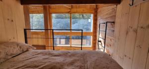 a bedroom with a bed in front of a window at Refugio PIREN, Corralco, Hot Tub y nieve in Curacautín