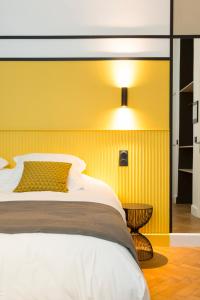 a bedroom with a bed and a yellow wall at Le Chat Qui Dort - Villa Gounod in Lille