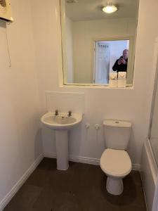 a man taking a picture of a bathroom with a toilet and sink at May Disc - Long Stay - Contractors in Bristol