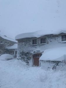 un edificio ricoperto di neve con la neve sopra di Habitaciones Frade a O Cebrero