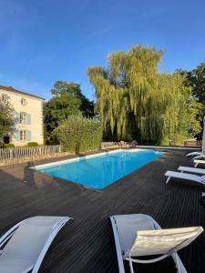 a swimming pool with two chairs and a tree at Domaine La Reveille in Dore-lʼÉglise