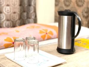 a coffee pot and two glasses on a table at HOTEL PRINCE ! NAINITAL Mall Road-prime-location in-front-of-Naini-lake hygiene-and-spacious-room in Nainital