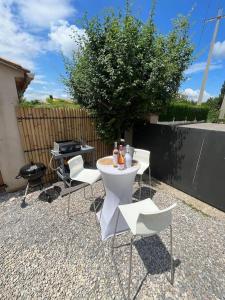 eine Terrasse mit einem Tisch, Stühlen und einem Grill in der Unterkunft La pause en luberon in Cavaillon