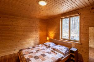 ein Schlafzimmer mit einem Bett in einem Holzzimmer in der Unterkunft CHATA JIZERKY ŠOLCŮV RYBNÍK in Raspenava