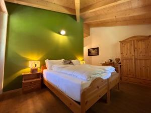 Un dormitorio con una pared verde y una cama en Agritur Maso Val Fraja, en Cembra