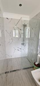 a bathroom with a shower with a marble wall at Kutal Parkinn Hotel in Përmet