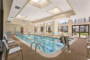 una gran piscina con sillas y mesas en un edificio en DoubleTree by Hilton Hotel Detroit - Novi en Novi