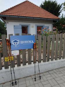 un cartel en dos postes delante de una casa en Boróka Apartmanház en Hárskút