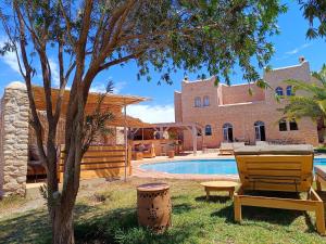una casa con piscina y un banco junto a un árbol en Villa Maya, en Essaouira