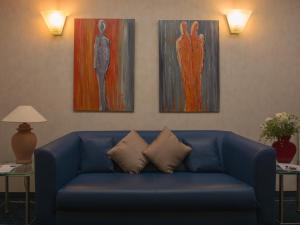 un sofá azul en una sala de estar con 3 pinturas en Hotel Haus Gimken, en Essen