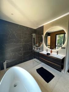 a bathroom with a tub and two sinks and a mirror at Villa haut standing avec piscine in Gradignan