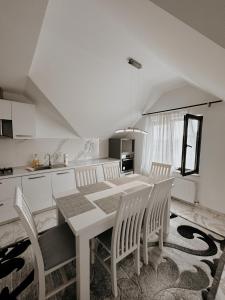 a white kitchen with a dining table and chairs at Cazare Vicoveancaa in Vicovu de Jos
