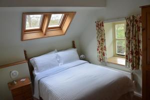 a bedroom with a white bed and two windows at Hafannedd in Corwen