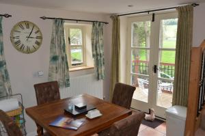 a dining room with a table and a clock on the wall at Hafannedd in Corwen