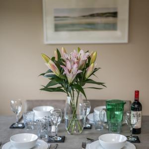 une table avec un vase de fleurs roses sur elle dans l'établissement Muirton Cottage, à Brechin