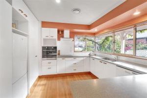 kuchnia z białymi szafkami i oknami w obiekcie Sweet Home w mieście Christchurch