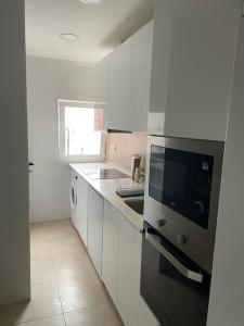 a kitchen with white cabinets and a stove top oven at Dafundo Family Flat in Cruz Quebrada