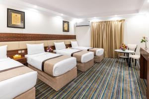 a hotel room with four beds and a table and chairs at Snood Ajyad Hotel Tower 1 in Makkah