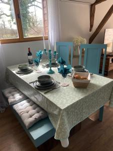 mesa de comedor con mantel blanco y sillas azules en La Petite Grange Gite, en Oradour-Fanais