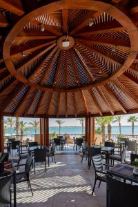 Safir Marsa Matrouh Resort في مرسى مطروح: مطعم بطاولات وكراسي وسقف خشبي كبير