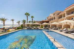 a swimming pool at a resort with chairs and umbrellas at Safir Marsa Matrouh Resort in Marsa Matruh