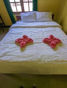 a bed with two red bows on it at Mushtinal Guest House in Ende
