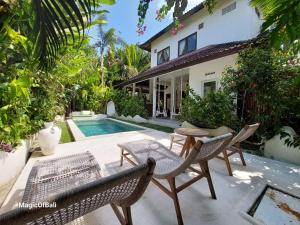 een patio met stoelen en een tafel naast een huis bij Medori Villa Seminyak in Seminyak