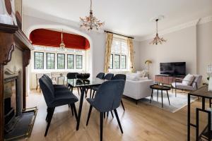 un soggiorno con divano bianco, tavolo e sedie di The Woking Wonder - Captivating 3BDR Flat with Parking a Woking