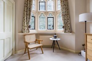 a chair and a table in a room with windows at The Woking Wonder - Captivating 3BDR Flat with Parking in Woking