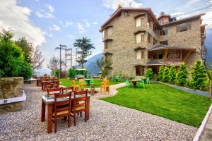 a building with chairs and tables in front of a yard at Snow City's Montana Blues Resort Manali - Heated & Air-Cooled Stay in Manāli