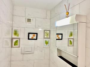 a white bathroom with plants on the wall at Green Sun - a cozy apartment close to the airport in Opfikon +3 photos