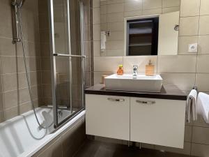 a bathroom with a sink and a shower and a tub at Coté Forêt in Orbey