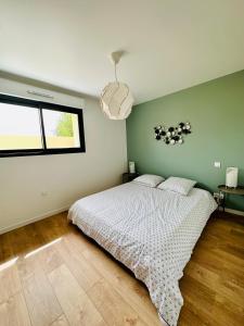 - une chambre avec un lit et un mur vert dans l'établissement La Halte Occitane - Logement neuf 6 personnes 3 chambres tout confort, à Montauban