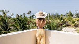 a woman in a hat standing on a balcony looking at palm trees at Avra Tatajuba in Tatajuba +43 photos