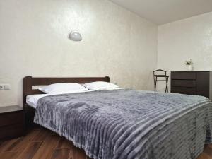 a bedroom with a bed with a blue comforter at Modern apartment on Belvedere in Ivano-Frankivsk