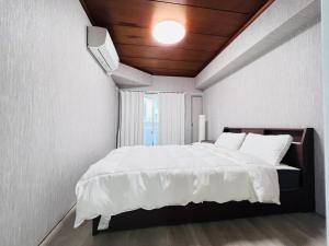 a bedroom with a large white bed with a ceiling at The Kojima in Tokyo
