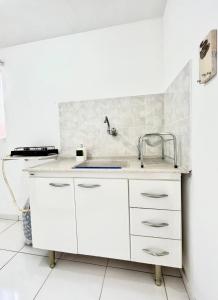 uma cozinha com armários brancos e um lavatório em Kitnet vila adyana em São José dos Campos
