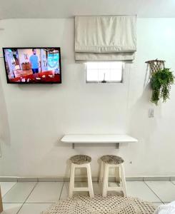 una mesa y dos taburetes en una habitación con TV en Kitnet vila adyana, en São José dos Campos