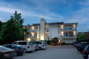 a large building with cars parked in a parking lot at Hotel Hiki in Bibione