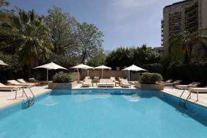 a large swimming pool with chairs and umbrellas at Park Hyatt Mendoza Hotel, Casino & Spa in Mendoza