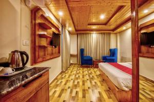 um quarto de hotel com uma cama e cadeiras azuis em Montana Blues Resort by Snow City em Manali