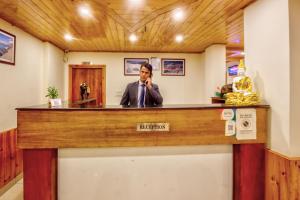 a man talking on a cell phone at a reception desk at Montana Blues Resort by Snow City in Manāli