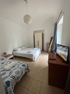 a bedroom with two beds and a desk with a television at Casa vacanze Il Gianduiotto in Turin