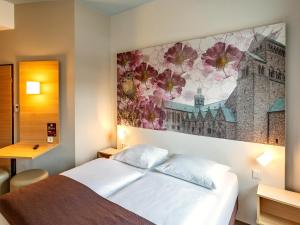 ein Schlafzimmer mit einem Bett und einem Wandgemälde in der Unterkunft B&B Hotel Hildesheim in Hildesheim